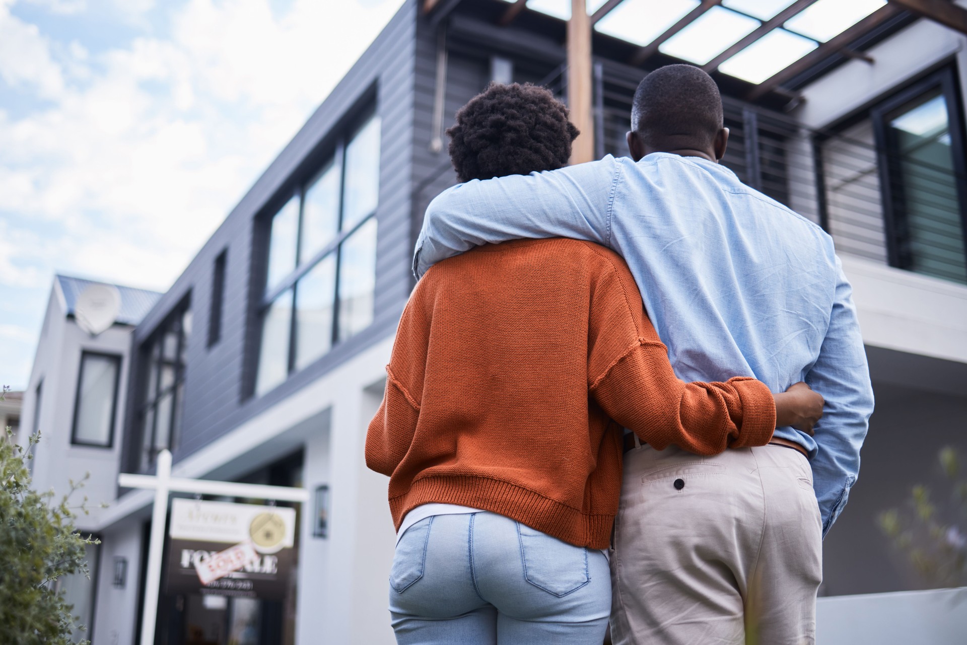 Rearview shot of a young couple standing outside their new home